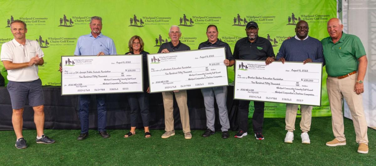 Representatives from local schools pose with large checks