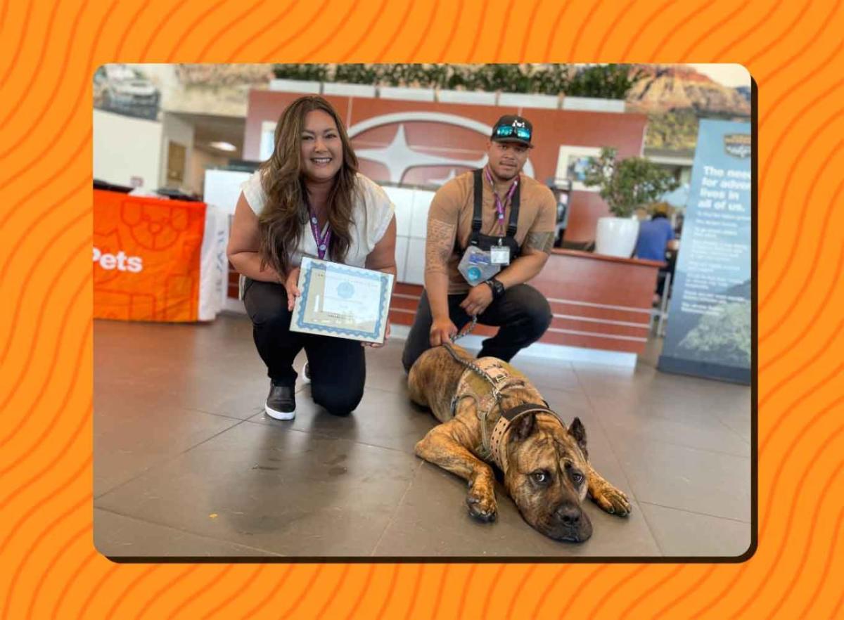 Two people with their dog and certificate of graduation.