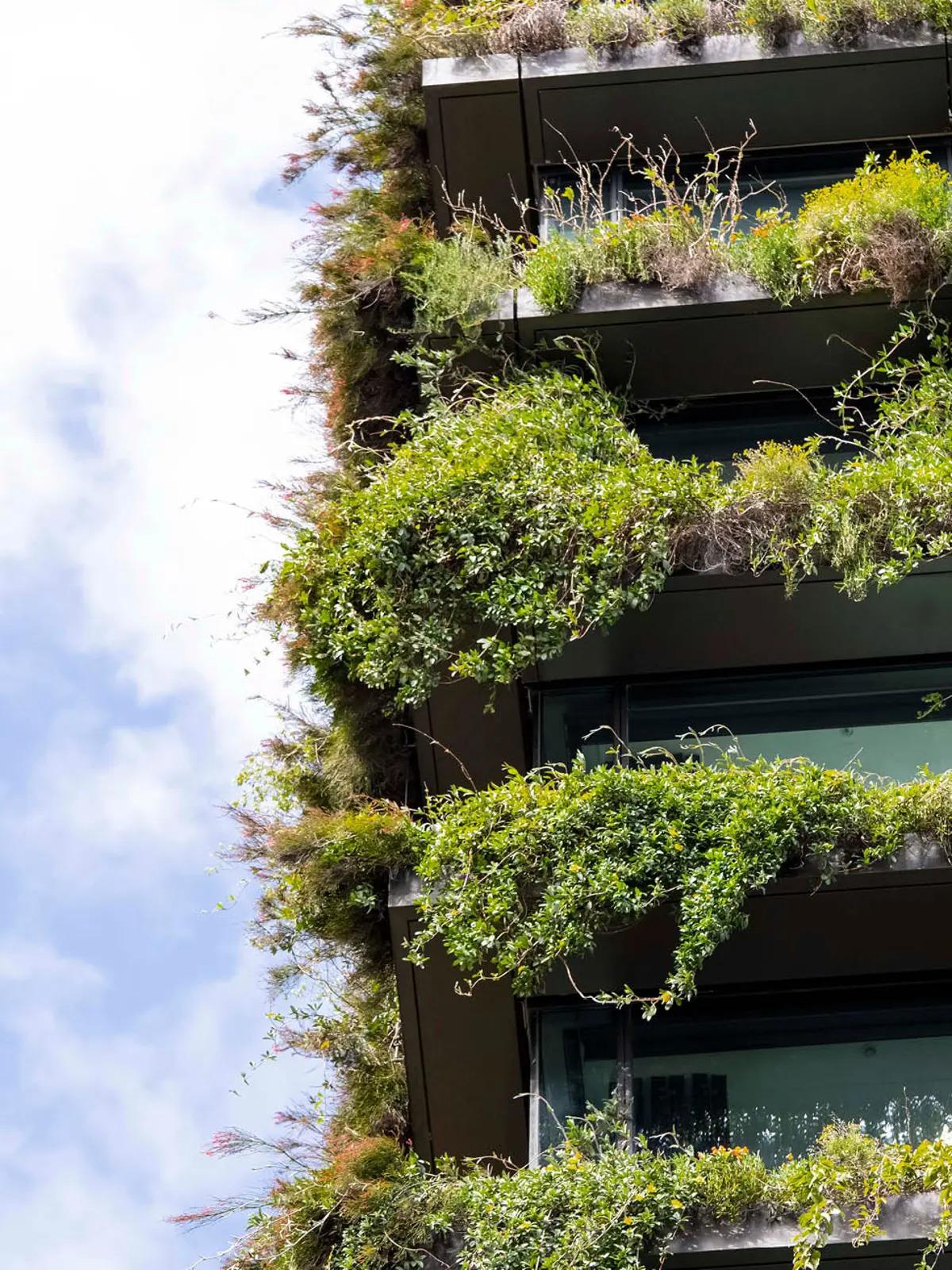 A multi-story building with overflowing plants on every balcony.