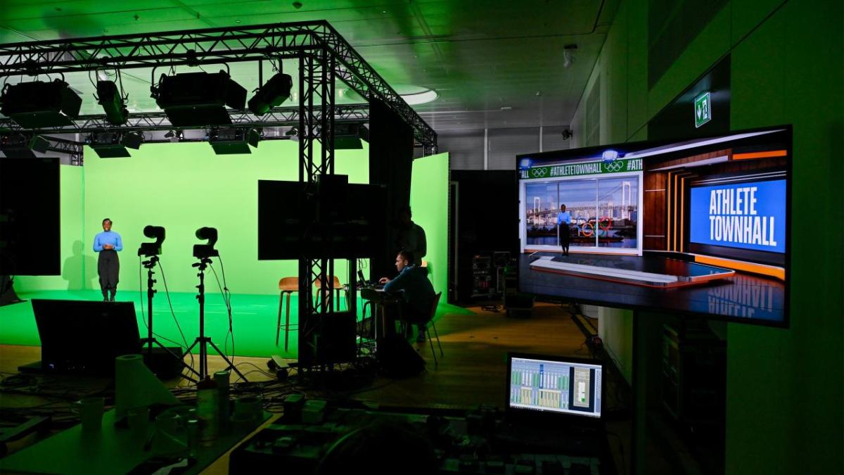 A person surrounded by green screens in a recording studio