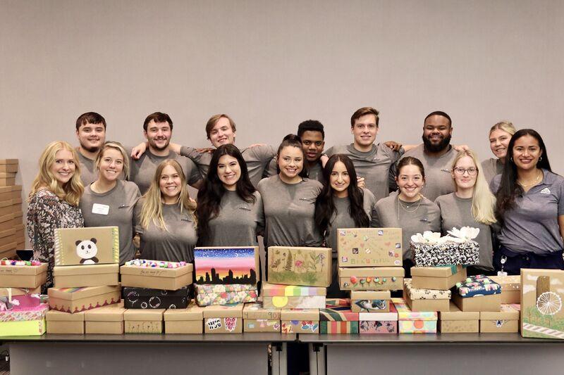 large group of people behind a table of stacked shoeboxes