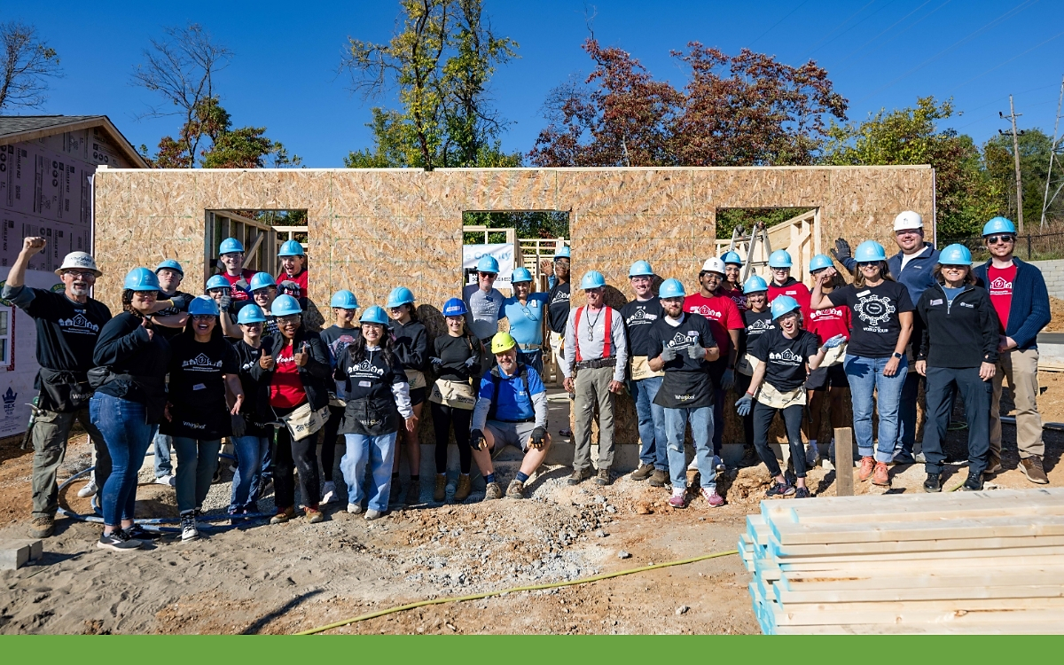 Whirlpool Corporation, Habitat for Humanity of Monroe County, and Indiana University’s Kelley School of Business are marking a major milestone in their long-standing collaboration: 15 years of building hope and homes together in Bloomington, Ind. This year’s build constructed five new net-zero homes in Bloomington’s Osage Place neighborhood as part of the BuildBetter with Whirlpool program, emphasizing the company’s deep commitment to sustainable housing and community building. A group of volunteers outside a home being built
