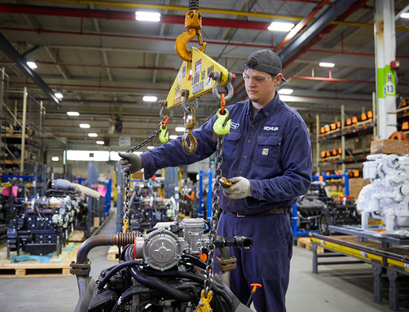 A person using a hoist to lift a piece of machinery