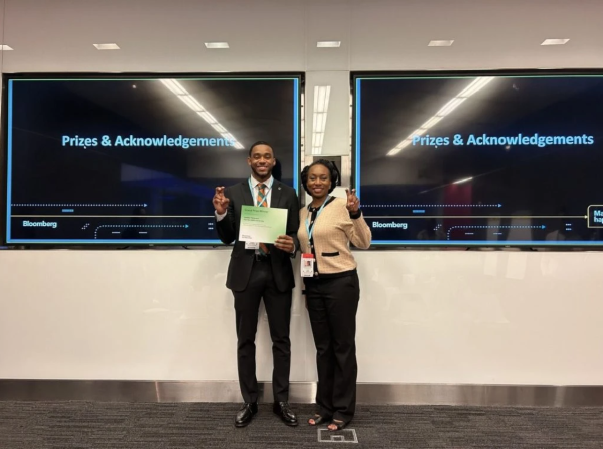 Two participants standing in front of digital displays, holding a certificate.