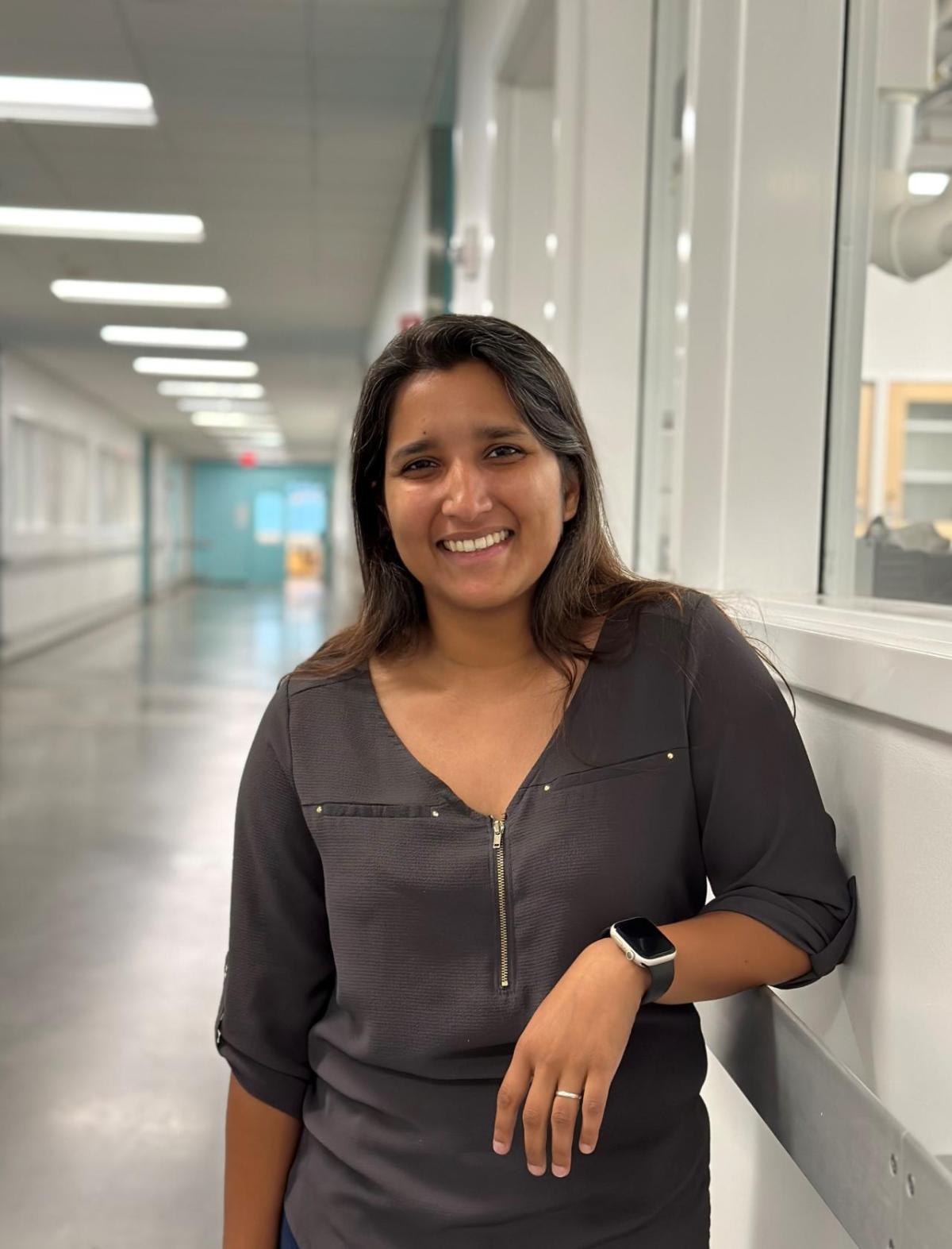 Woman standing in the corridor of an R&D lab looking at the camera and smiling.