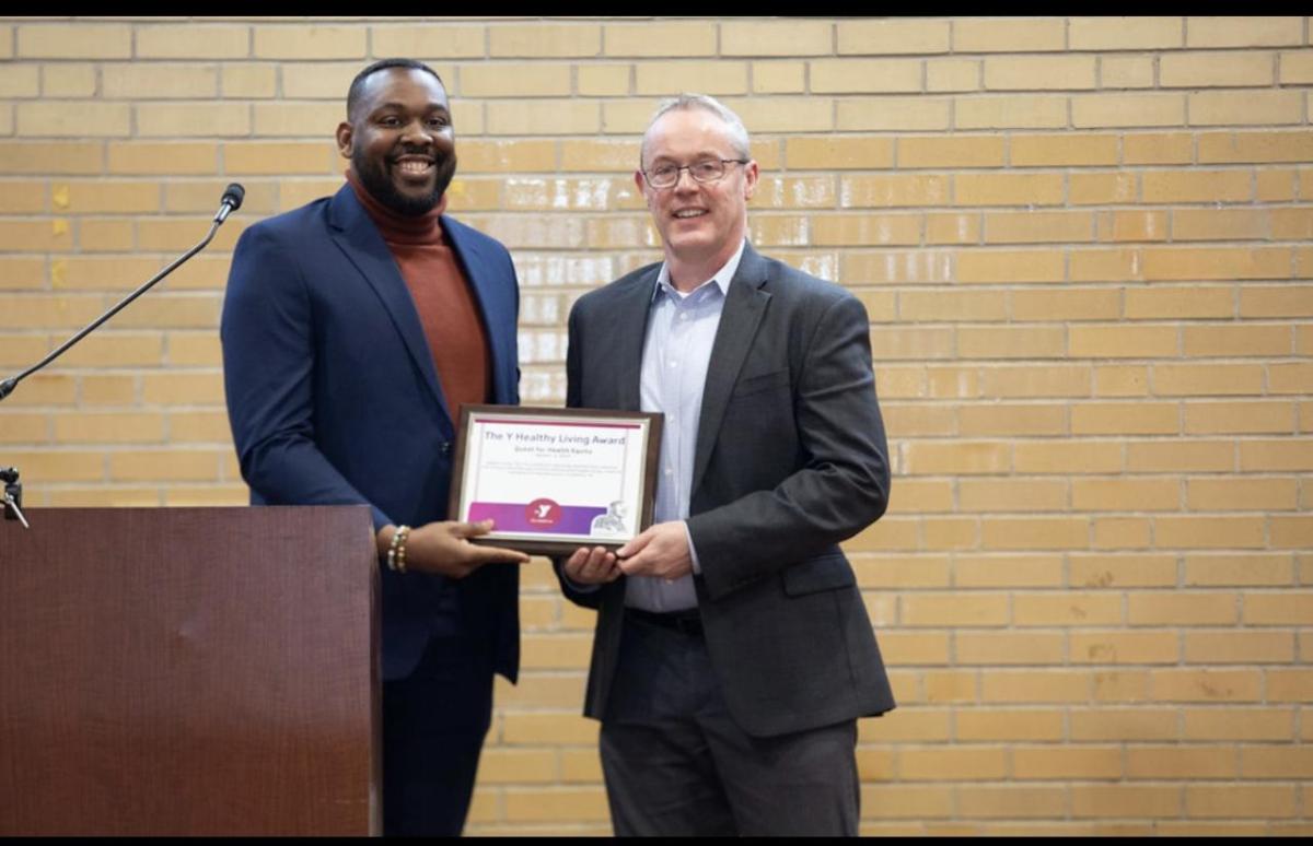 Two people holding a plaque behind a podium.