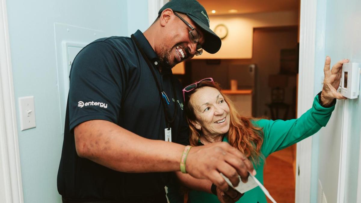 An Entergy employee helping a customer adjust a thermostat