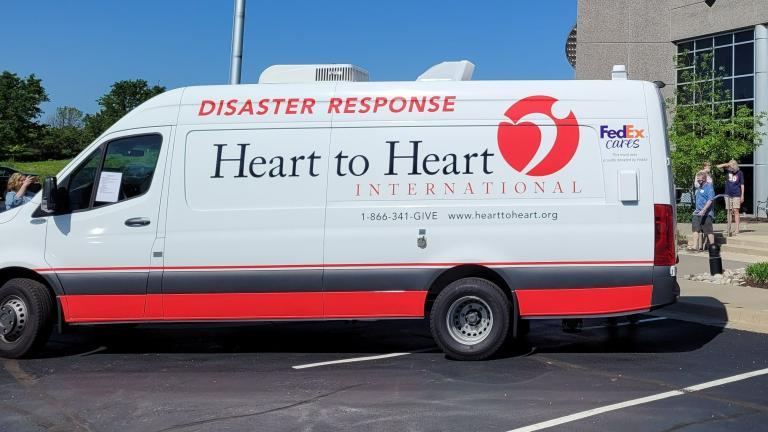 large van with "heart to Heart" and FedEx Cares logos in a parking lot