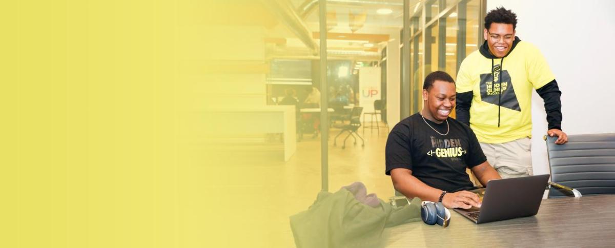 Two men on a laptop wearing "Hidden Genius" t-shirts