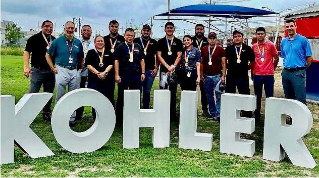 Kohler employees outside behind a large Kohler sign