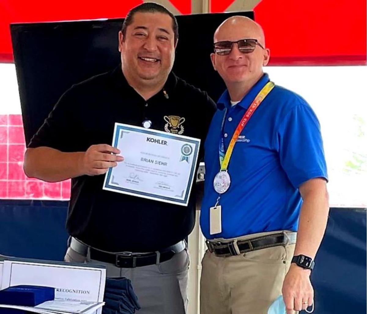 Martin in a black shirt holding a certificate next to a man in a blue shirt