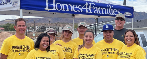 A group of volunteers posed in front of a Homes 4 families booth.