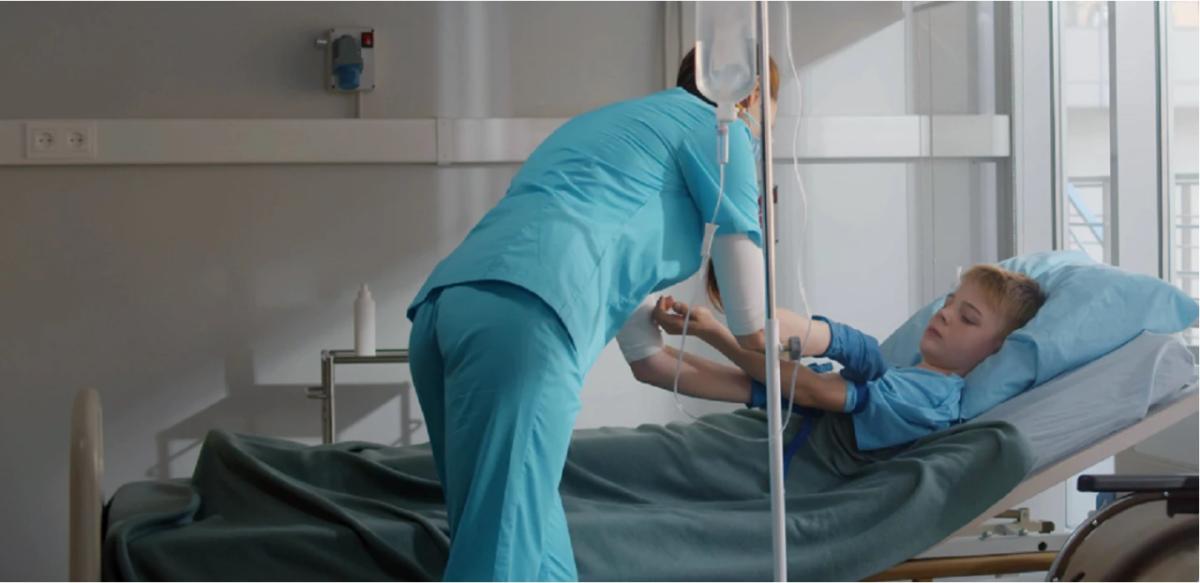 Child getting an IV in a hospital bed