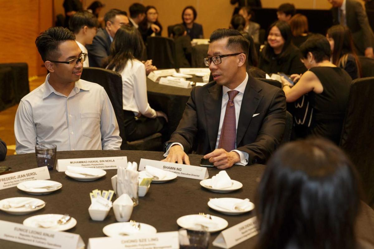 People sitting together and talking at a round dinner event table