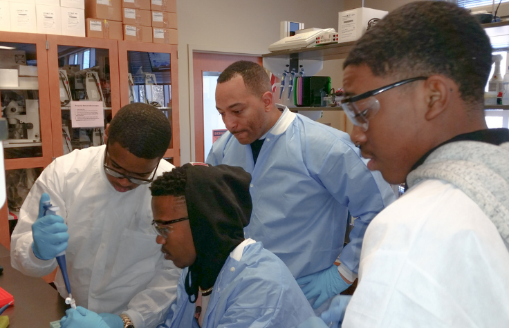 Dr. Arik King in the lab with the same group of young men of color. 
