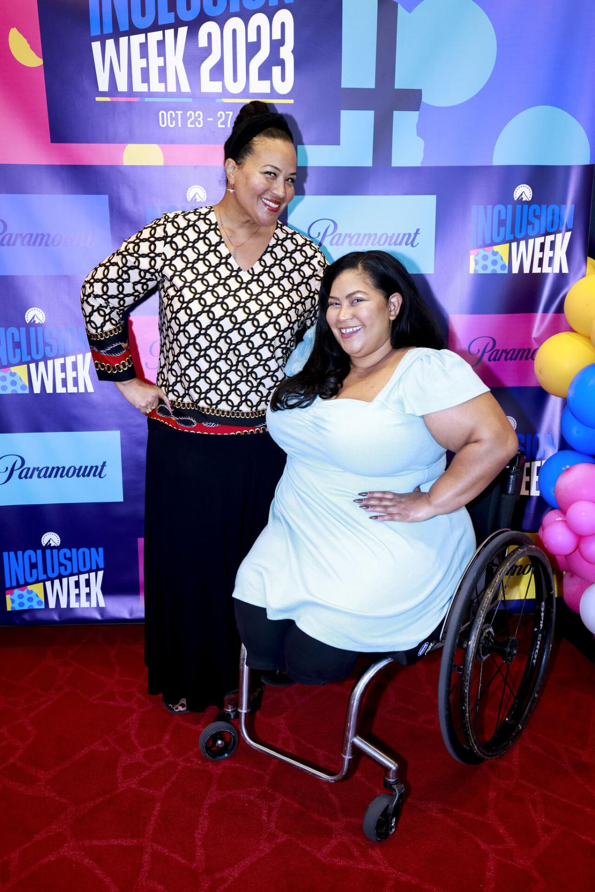 Two people pose on a red carpet. "Inclusion Week 2023" behind them.