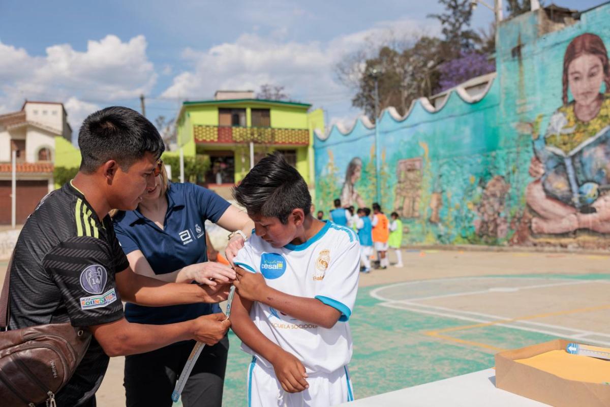 Two adults measuring a child's arm