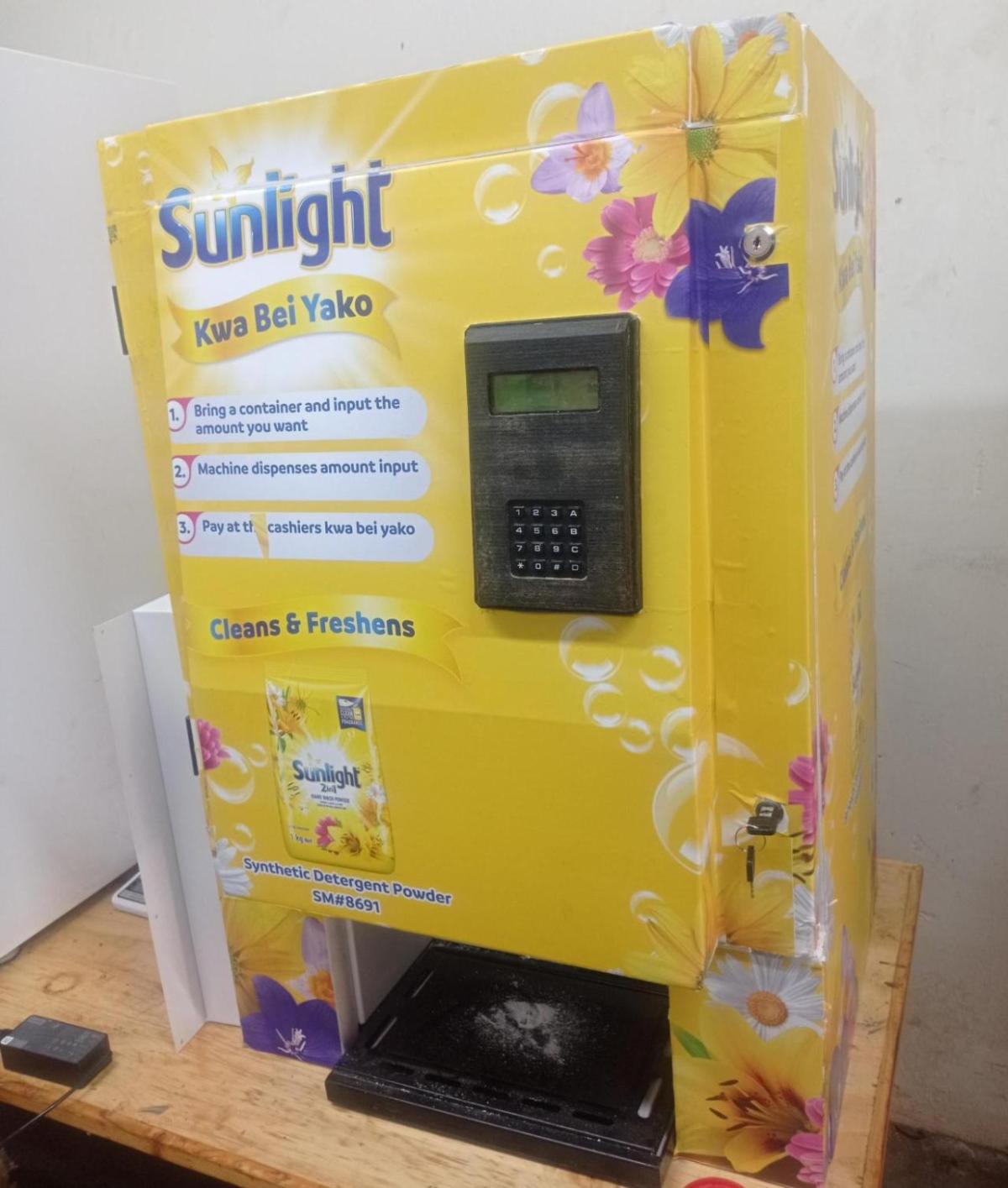 A bright yellow vending machine with "Sunlight detergent" logos.