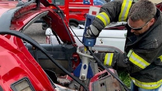 A firefighter using a tool to open a car door.