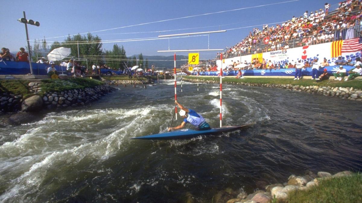 a kayaker in a water course. Spectators watching from the stands