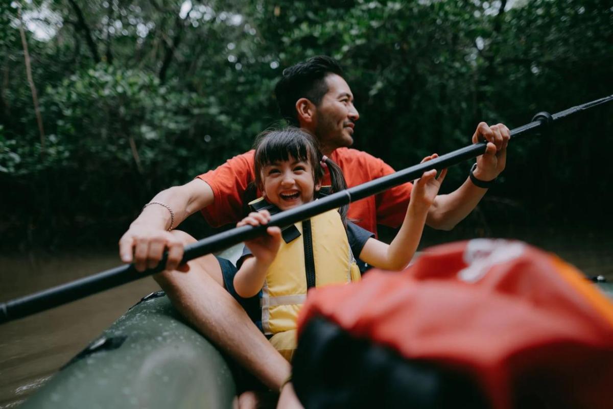 An adult and child kayaking in a body of water.