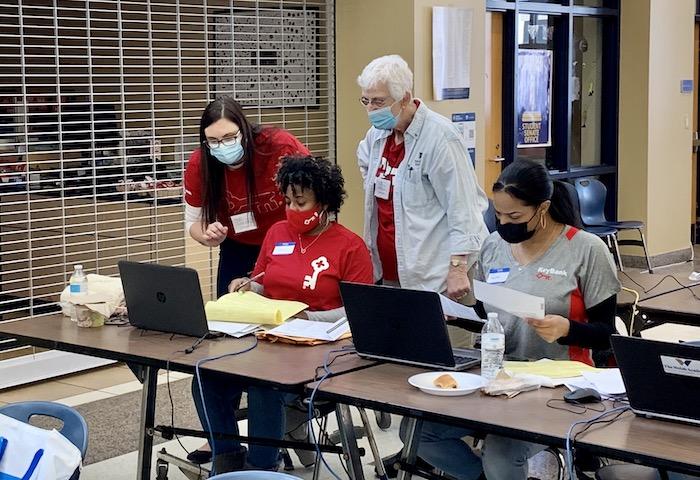 Four KeyBank volunteers seated in front of laptops ready to assist. All are wearing KeyBank red t shirts.