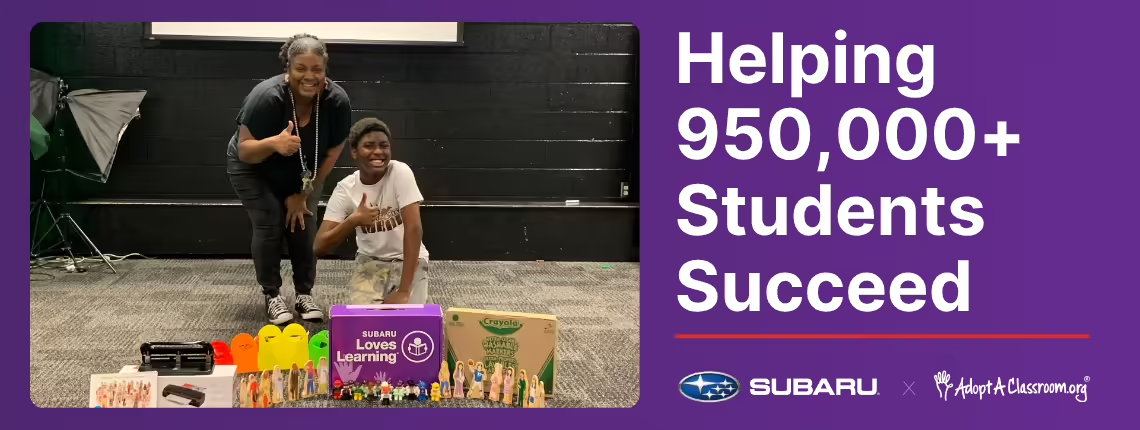 A student and an adult behind school supplies, giving thumbs up