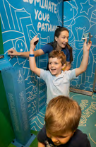 A child cheering by an adult pointing to a wall with writing on it. 