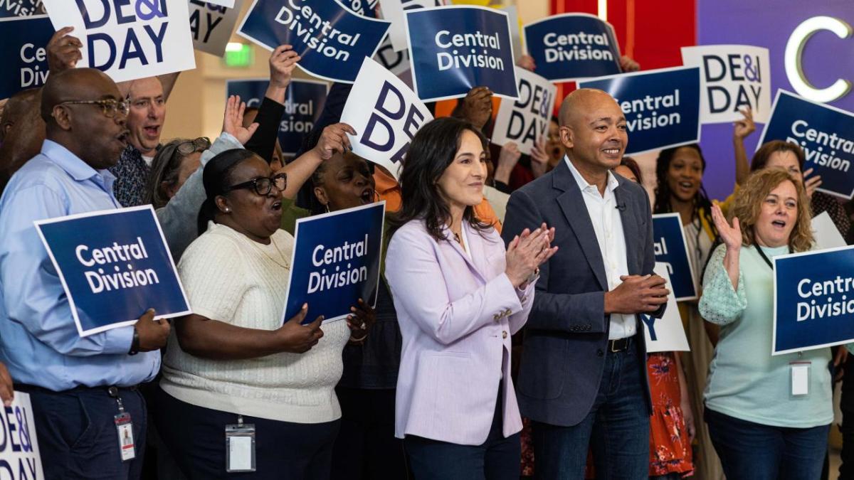 Kim Kleinhans and  Jason Gumbs in front of people holding DE&I Day signs