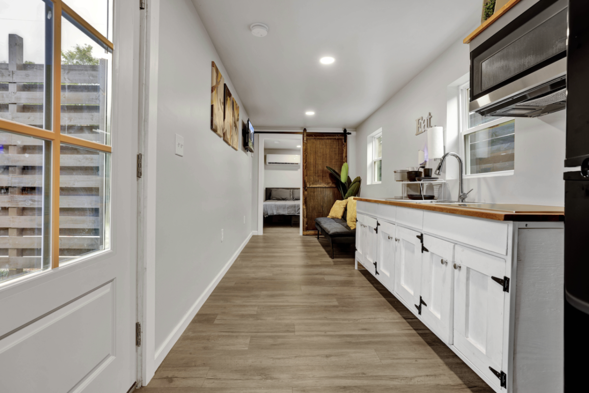 Kitchen with white cabinets & custom wood counter tops in up-cycled shipping container 