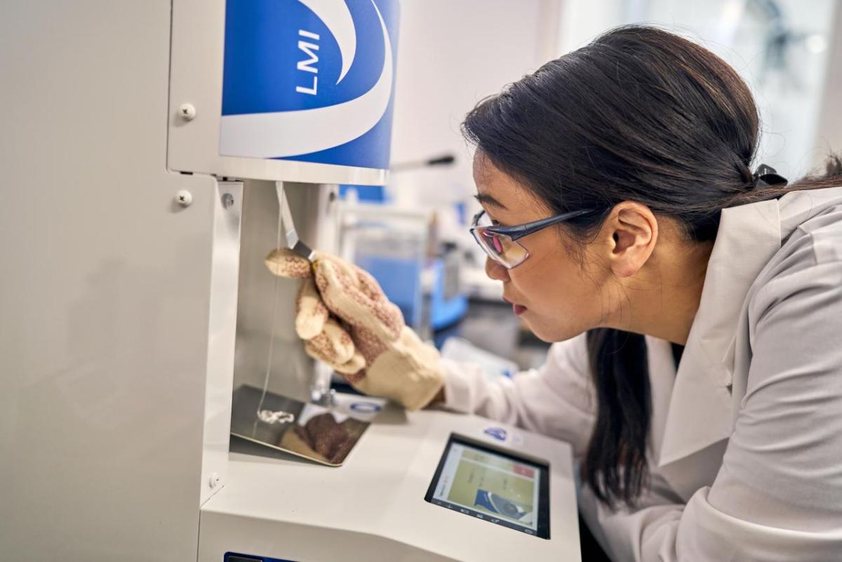 Photo of An Nguyen (Technical Application Specialist) Lab worker performs a test using a machine