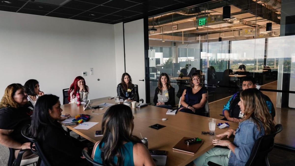 A conference room with a full table of seated peopl.