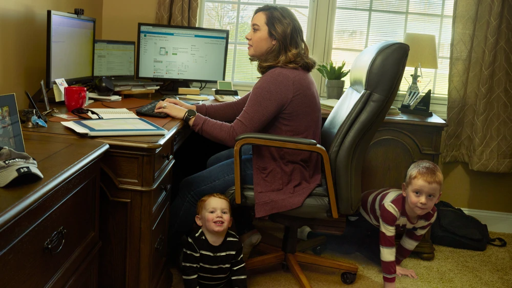 Woman working at a desk with kids crawling beneath her chair