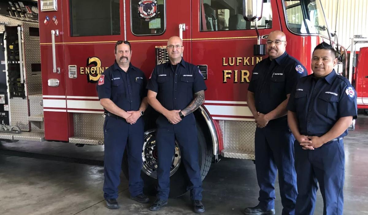 four firefighters standing by a fire truck