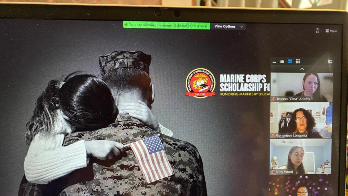 A laptop screen displaying a veteran hugging a child who is holding the American flag
