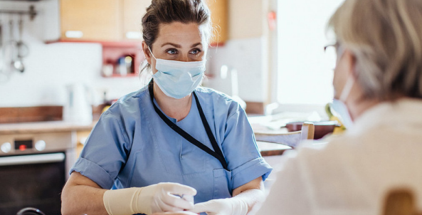 Masked person in scrubs talking to patient