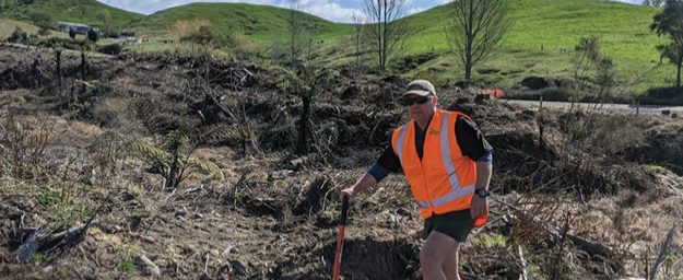 a person in reflective vest standing in a forest restoration patch