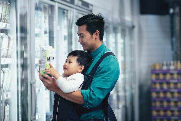 Photo courtesy of GreenBiz Father with a baby carrier looking at milk label