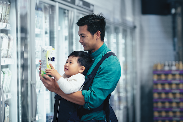 Father with a baby carrier looking at milk label