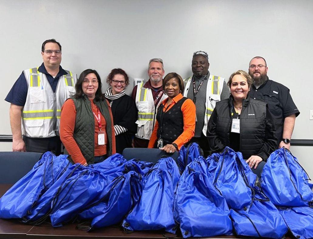 group of volunteers behind a pile of stuffed blue sacks