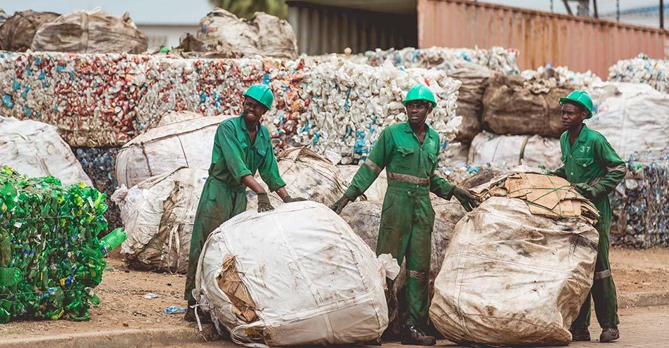 three people cleaning up plastic recycling 