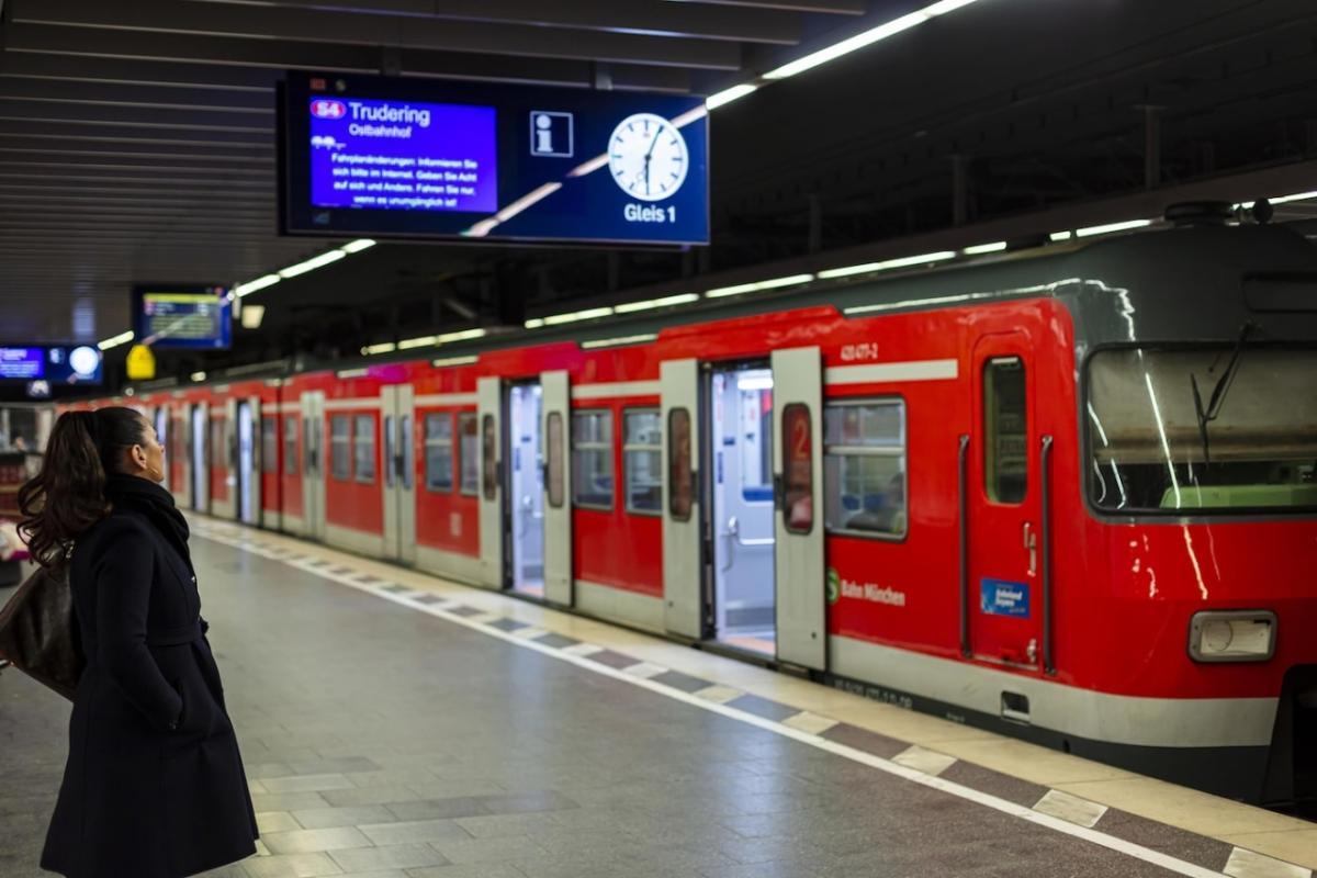 a person waiting on an underground train platform, a train with open doors in front of them