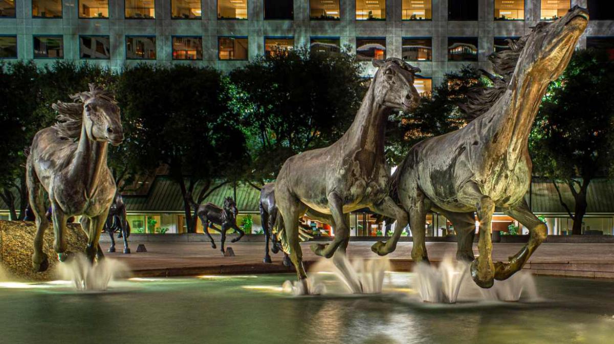 Large outdoor statues of three horses splashing in a water feature.