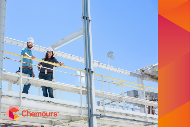 Two people in hard hats standing on a high walkway