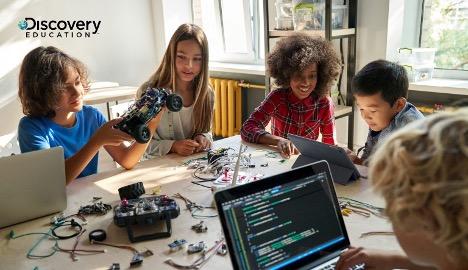 Young people work at a table on computers and electronics