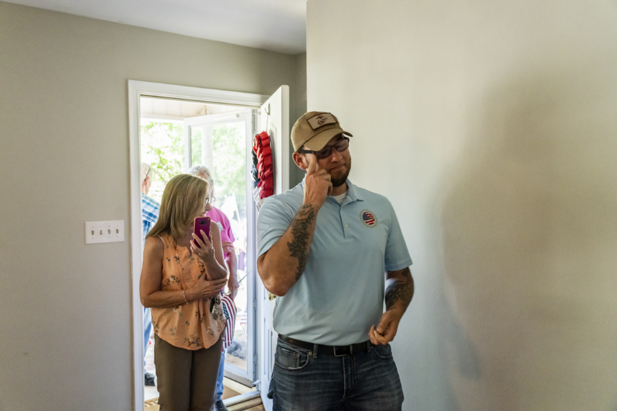 Sgt. David Long wipes a tear as he and another person enter the home