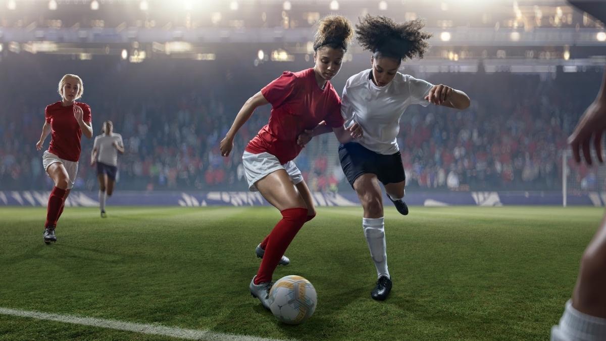 Female soccer players competing for the ball in a game.