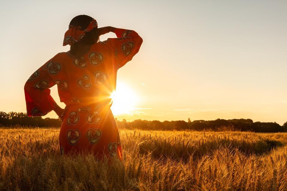 Woman in field with the sun setting