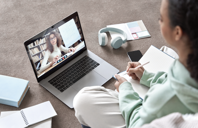 A student having an online lesson from a teacher on a laptop screen