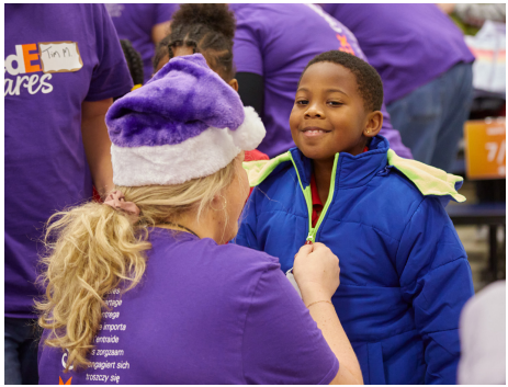 An adult helps a child zip a coat on.